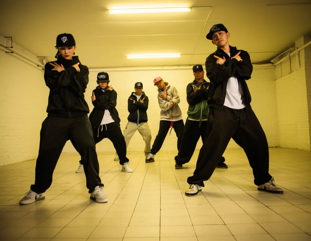 Six dancers holding a sharp freeze in the hip-hop class